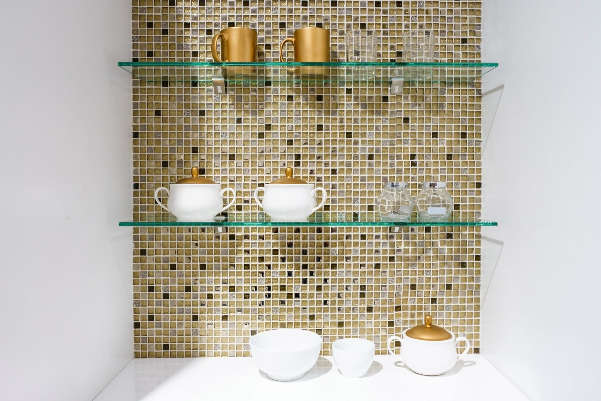 Gold tile with glass shelving and white and gold dishes