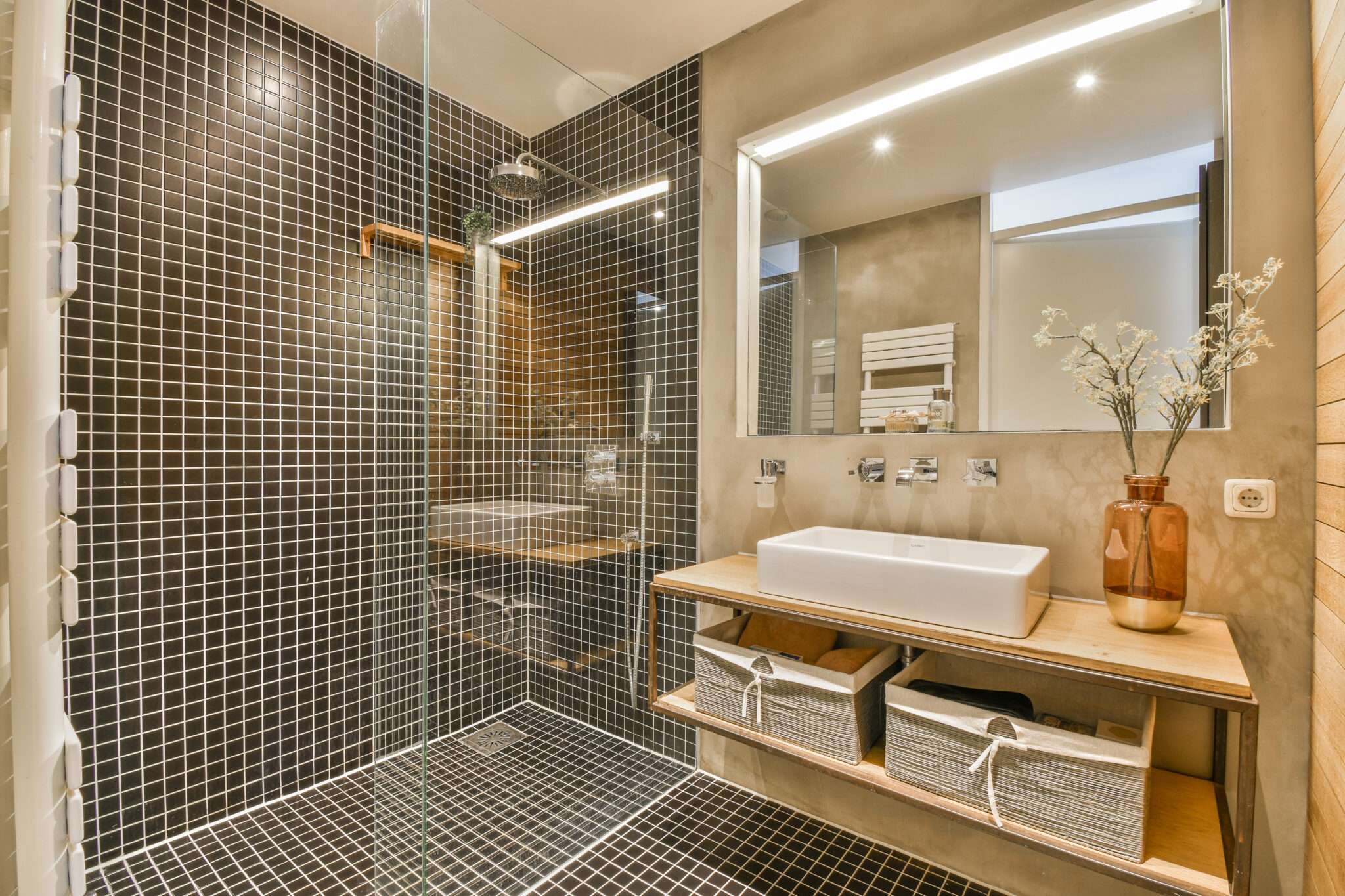 Glass shower door in black tile bathroom