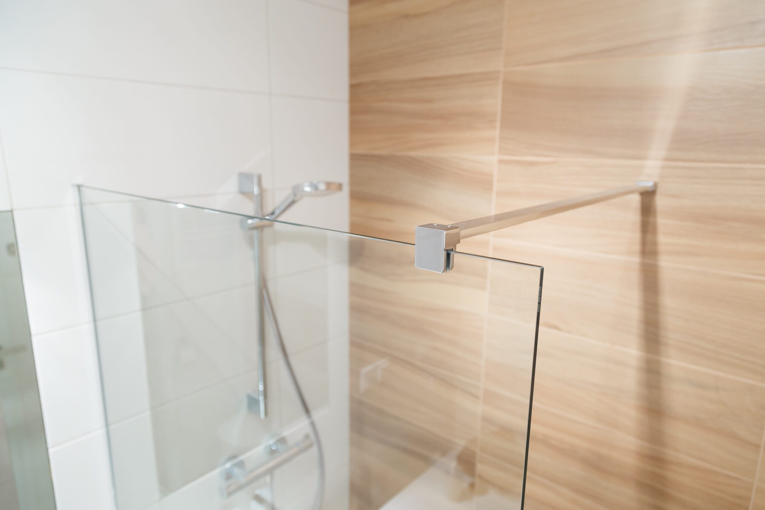 Top of glass shower enclosure with metal bracket clamp