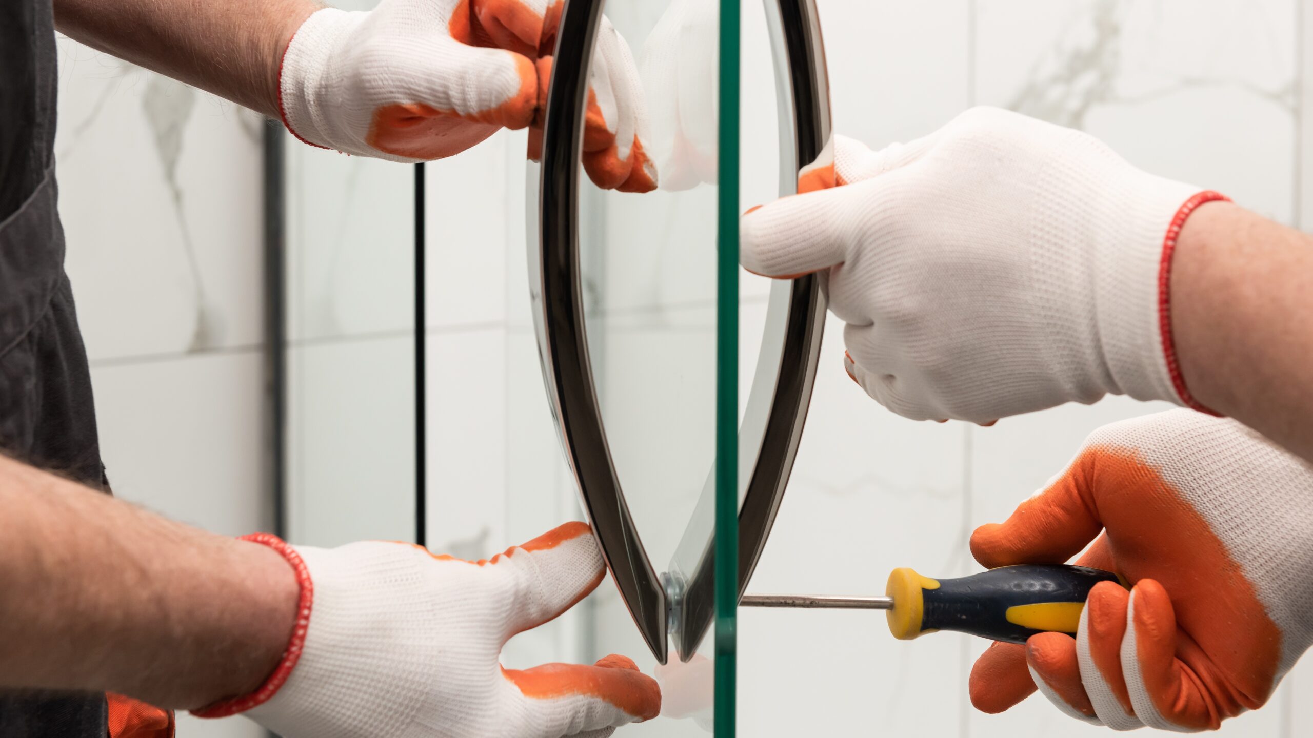 Close-up view of two technicians installing a glass shower door enclosure